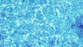 Top View of Young Woman Swimming in Clear Blue Water