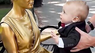 Um bebezinho dá beijinhos em uma estátua