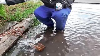 Clearing a flooded road by manually unblocking a clogged drain.