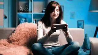 Beautiful Woman Chatting and Using Phone on Sofa at Night