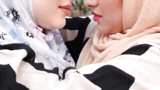 Wanita berhijab saling berciuman mesra.