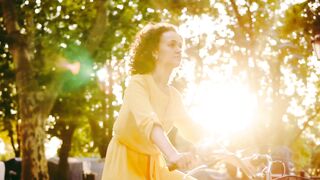 Beautiful Girl Riding City Bike in Park During Golden Dawn