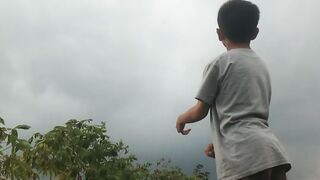 Young Boy Playing Outdoors on a Grassy Field Under a Cloudy Sky