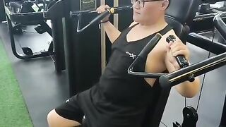 Asian Man Doing Shoulder Press Machine Workout At Modern Gym