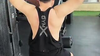 Read view of Asian man doing Lat pulldown machine exercise for back back muscles at gym