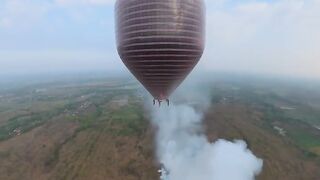 Serial view from hot air balloon dropping smoke firecrackers over dry field
