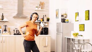 Cute Woman Enjoying Music While Dancing in Her Kitchen