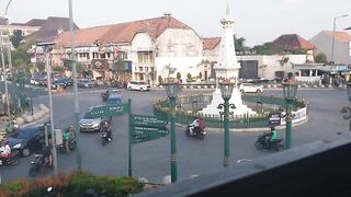 The scene at the Tugu Yogyakarta Tugu Pal Putih intersection featuring a steady flow of motor vehicles and cars in the late afternoon