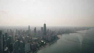 Drone footage of Chicago skyline with Lake Michigan on a hazy day.