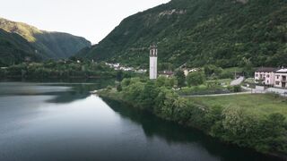 Serene aerial view of a peaceful lakeside village surrounded by lush green hills and calm waters.