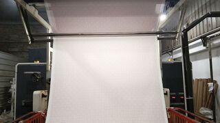 White textile fabric moving on industrial weaving machine in garment factory