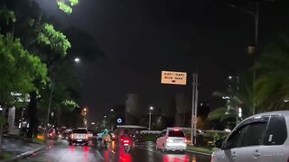Night rain slicks the road, reflecting city lights
