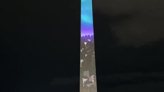 Tall monument glows with vibrant colors at night