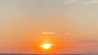 Golden sunset over ocean beach with gentle waves rolling on sandy shore