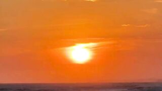 Golden sun setting over ocean waves on beach shoreline