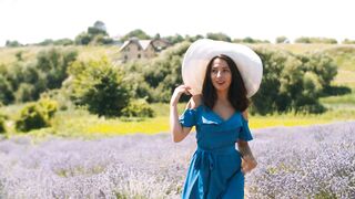 Charming Woman in Trendy Blue Dress Walking Through Fragrant Lavender Blossoms
