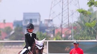 Young Girl Equestrian Rider In Formal Attire Riding Brown Horse In Sandy Arena Training With Instructor
