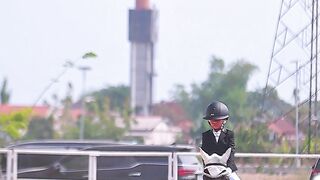 Cinematic frontal tracking of young girl in black formal equestrian uniform riding black horse