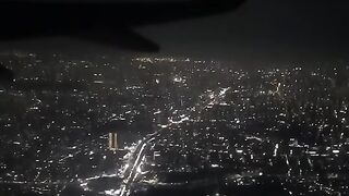 Airplane Wing Silhouette over Glowing City Grid at Night