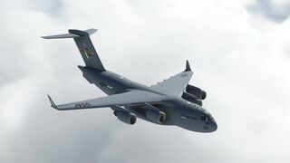 Boeing C-17 Globemaster airplane flying though clouds over the ocean