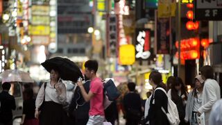 Pedestrian walk in Tokyo Entertainment district in Tokyo, Japan with a pedestrian walk with people among buildings filled with luminous LED