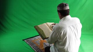 Man reading Quran on green scan