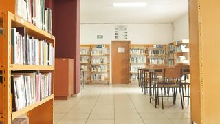 Walking down a library corridor with tables and bookcases