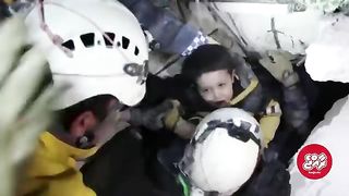 A Syrian boy smile after being pulled from the rubble