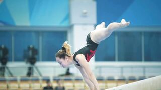 Athletic woman gymnasts performing on  bar at the championship