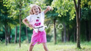 Positive little girl dancing happily in the park