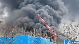 A worker hops from crane to another to escape the burning construction site