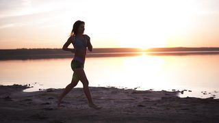 plus sized woman in shorts running along the ocean